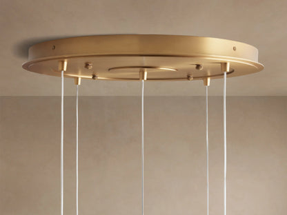 Casen Round Chandelier's circular satin brass ceiling mount, seen from below, with several white wires hanging.