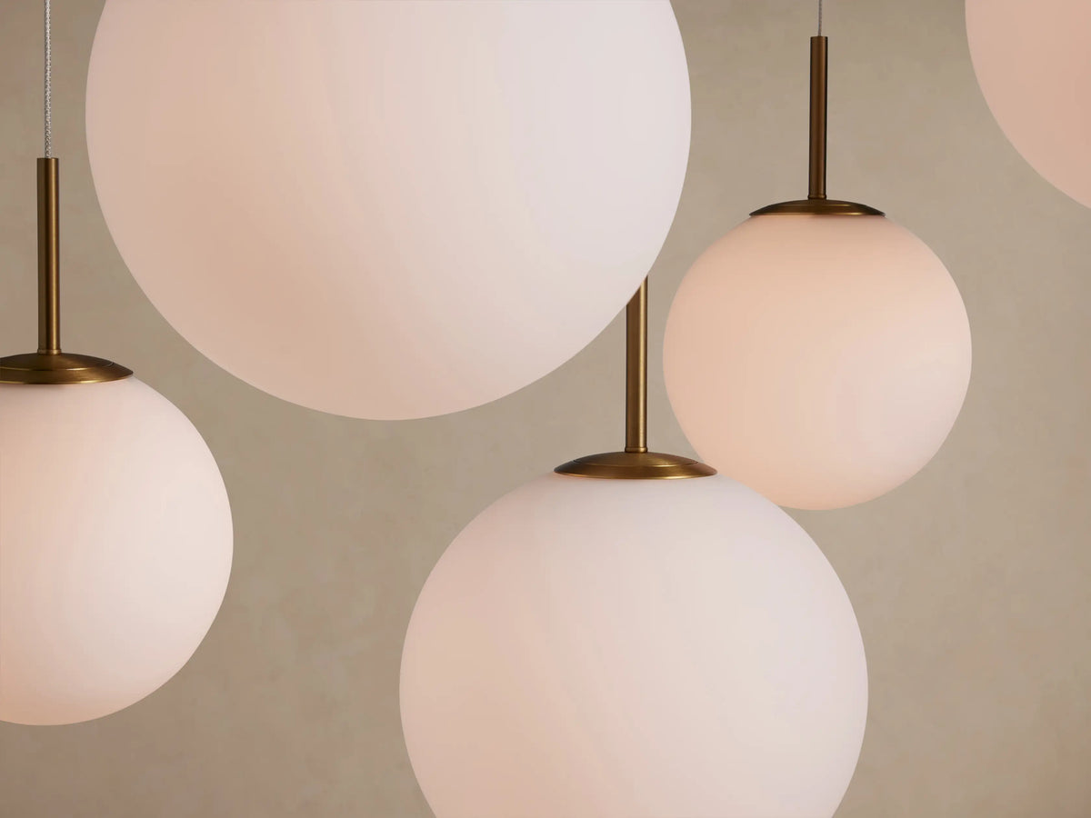 Multiple white opal glass globes of Casen Round Chandelier, varying sizes, hanging from satin brass stems.