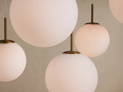 Multiple white opal glass globes of Casen Round Chandelier, varying sizes, hanging from satin brass stems.