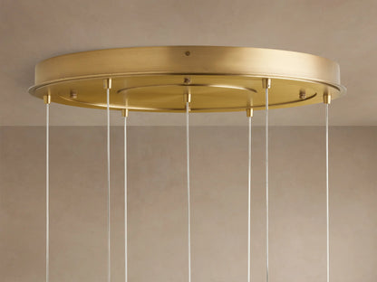 Close-up of Casen Round Chandelier's satin brass ceiling canopy with many thin white hanging cables against a beige ceiling.