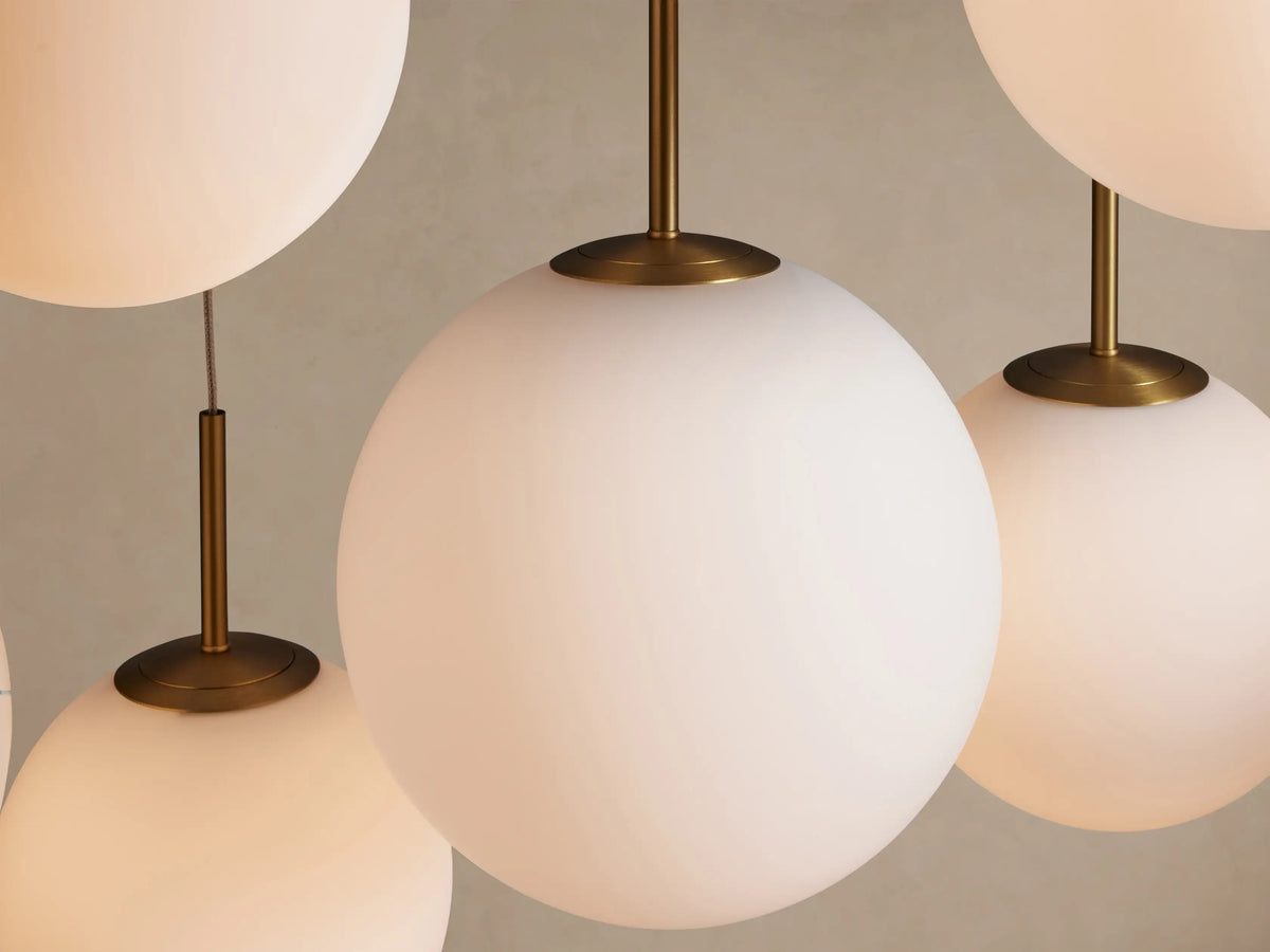 Casen Linear Chandelier with 10 white opal glass globes and satin brass accents, suspended at varying heights on a beige background.