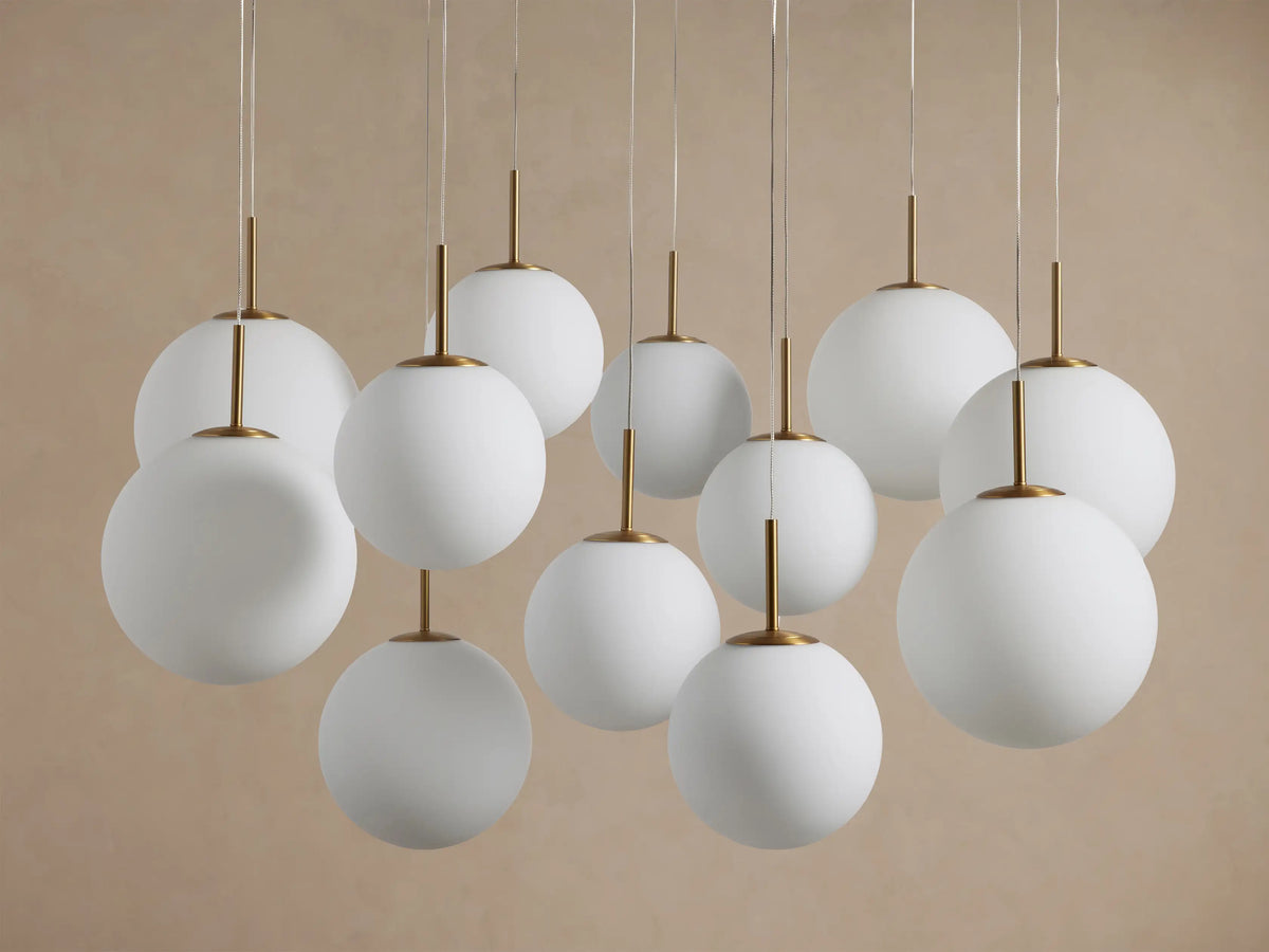 Casen Round Chandelier with multiple white opal glass globes suspended at varying heights, connected by satin brass rods.