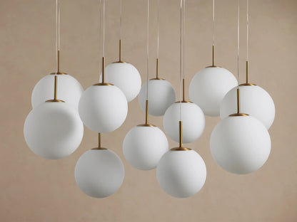 Casen Round Chandelier with multiple white opal glass globes suspended at varying heights, connected by satin brass rods.
