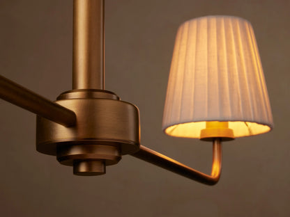Adria 2-Light Chandelier: brass-toned iron hanging fixture with a horizontal bar and two white pleated shades on a beige wall.