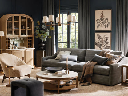 Adria Round Chandelier with five illuminated pleated white shades on a brass-finished frame, hanging against a dark wall.