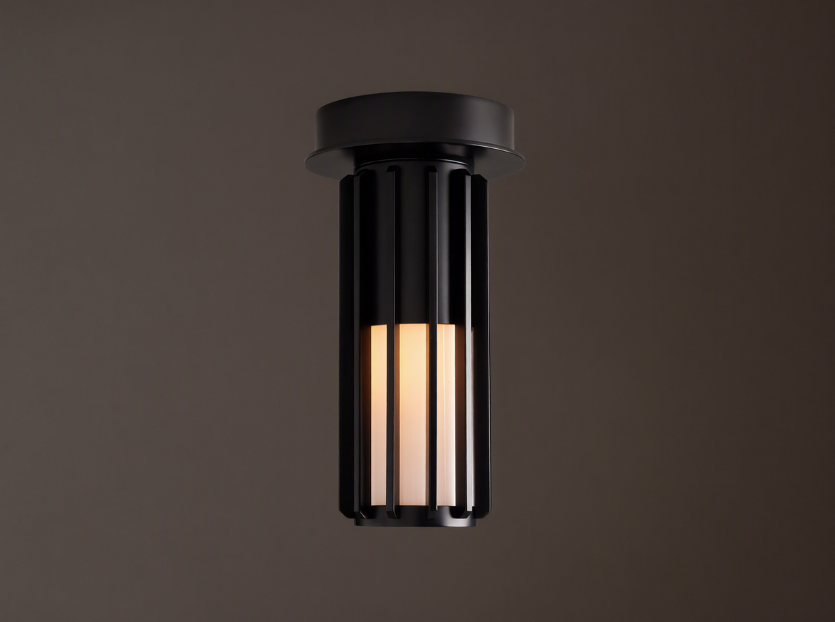 Matte black Gabbia Outdoor Spotlight Flush Mount, cylindrical with vertical slats, flush-mounted to a light brown ceiling. Inner milk glass panels glow.