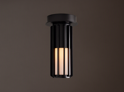 Matte black Gabbia Outdoor Spotlight Flush Mount, cylindrical with vertical slats, flush-mounted to a light brown ceiling. Inner milk glass panels glow.