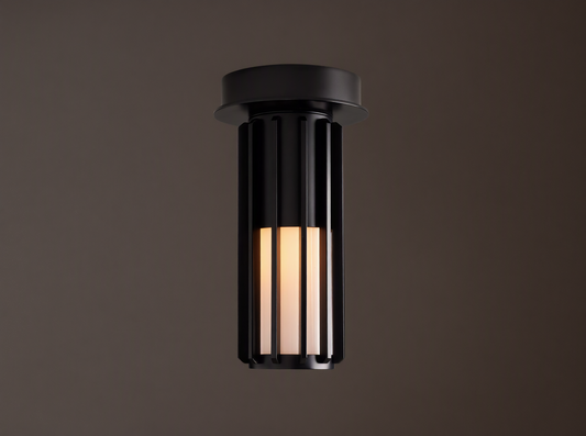 Matte black Gabbia Outdoor Spotlight Flush Mount, cylindrical with vertical slats, flush-mounted to a light brown ceiling. Inner milk glass panels glow.