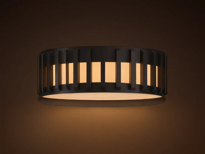 Gabbia Outdoor Flush Mount, matte black round light with vertical slatted shade & glowing milk glass, mounted on a ceiling.