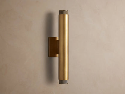Brass Spotlight Outdoor Sconce, cylindrical, mounted vertically on a wall, with dark knurled end caps.