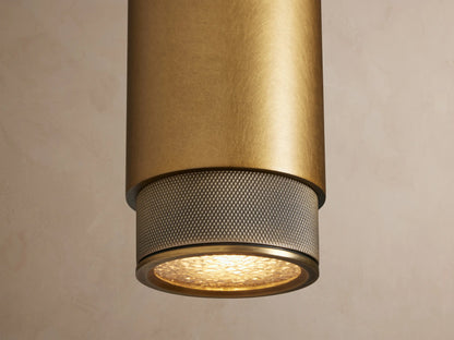 Brass Spotlight Outdoor Sconce, cylindrical and vertical, with dark gray knurled end caps, mounted on a light beige wall.