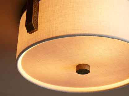 Emmet Flush Mount: White linen drum shade with textured antiqued brass frame & brass finial, mounted on a light ceiling.