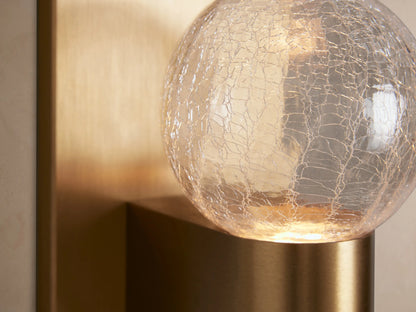 Casen Sconce: Vertical satin brass backplate, arm holding a clear crackle glass globe, mounted on a light wall.