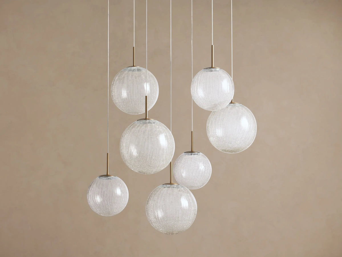 Casen Round Chandelier with multiple crackle glass globes hanging at varying heights, accented with satin brass details.