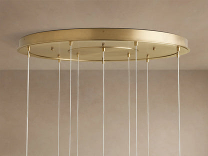 Casen Round Chandelier with a round satin brass canopy mounted on a light-colored ceiling, multiple clear cables hang down.