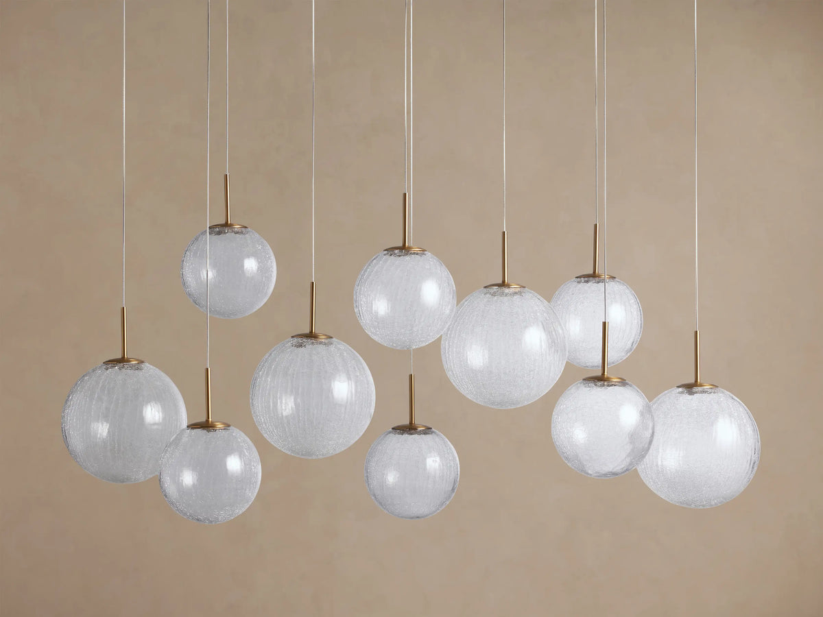 Casen Linear Chandelier with ten clear crackle glass globes, illuminated and hanging at various heights, featuring satin brass accents.