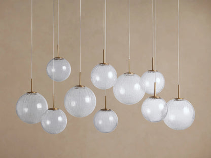 Casen Linear Chandelier with ten clear crackle glass globes, illuminated and hanging at various heights, featuring satin brass accents.