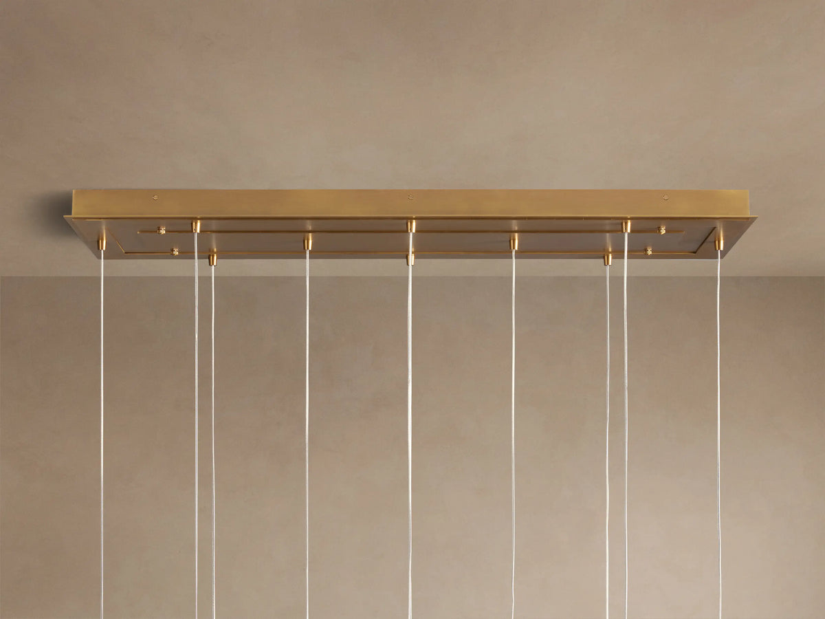 Close-up of Casen Linear Chandelier with illuminated crackle glass globes and satin brass accents, casting a warm glow.