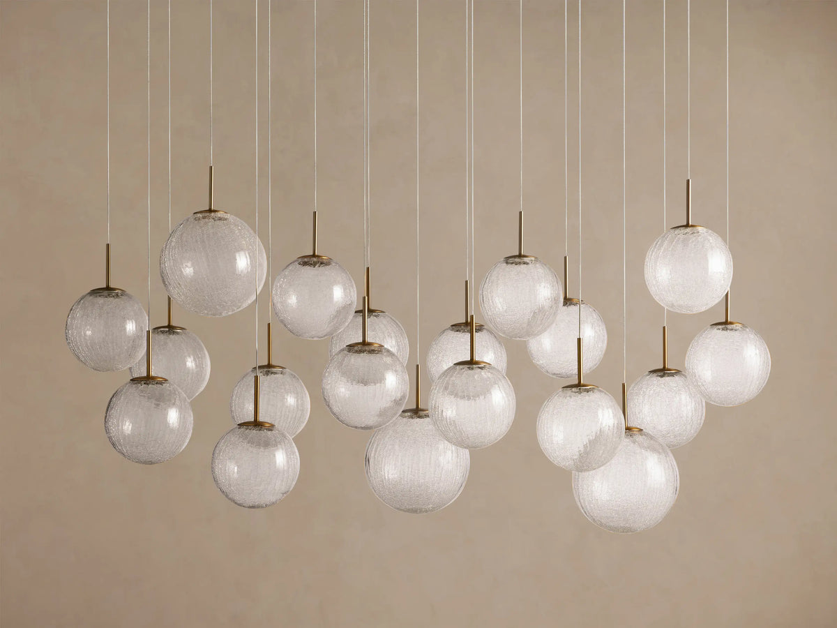 Casen Linear Chandelier: Many illuminated crackle glass globes with satin brass accents, suspended at varied heights.
