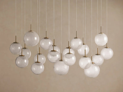 Casen Linear Chandelier: Many illuminated crackle glass globes with satin brass accents, suspended at varied heights.