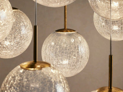 Casen Linear Chandelier featuring multiple clear, crackled glass globes suspended at varying heights with brass accents.