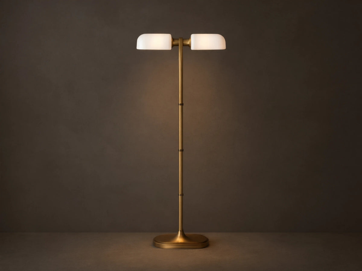 Zayd Floor Lamp: elegant brass with two illuminated oblong opal glass shades and an oval base, standing on a wooden floor.