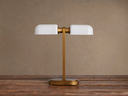 Zayd Table Lamp: modern brass base and stem, supporting two glowing horizontal opal glass shades, on a dark wooden table.