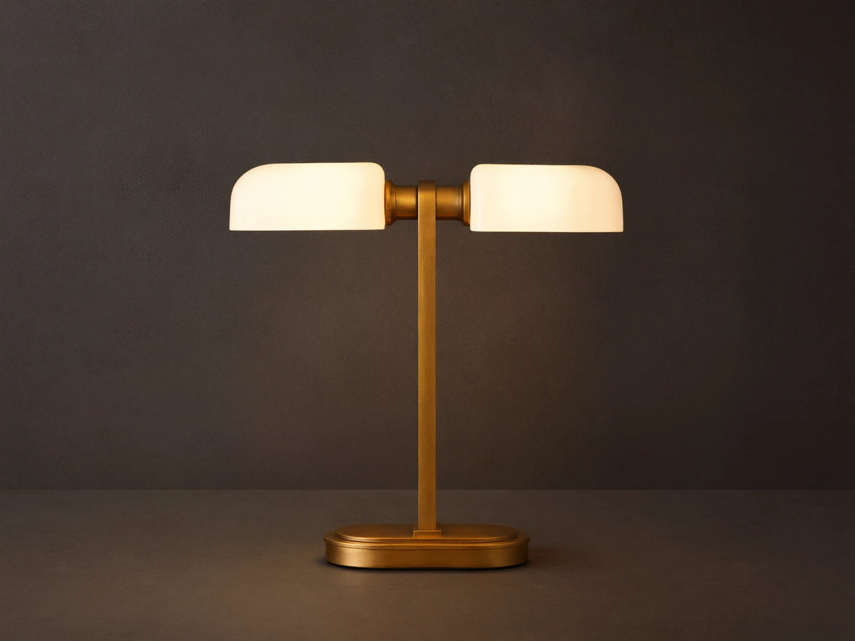 Zayd Table Lamp: modern brass base and stem, supporting two glowing horizontal opal glass shades, on a dark wooden table.
