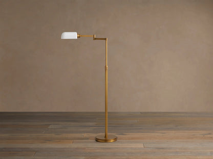Zayd Swing Arm Floor Lamp, brass with an extended arm, illuminated opal glass shade, on a wooden floor.