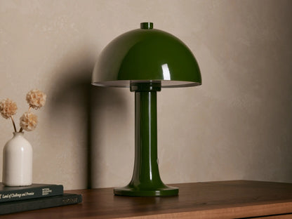 Jocy Portable Table Lamp, dark green lacquered metal, mushroom-shaped, illuminated on a wooden table. Books & vase nearby.
