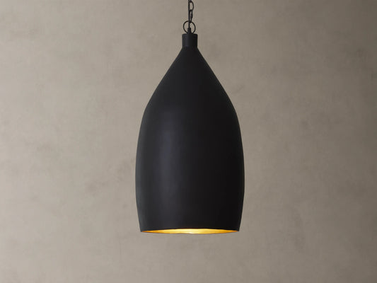 A matte black pendant light with a smooth, teardrop shape hanging from a chain against a beige textured wall.