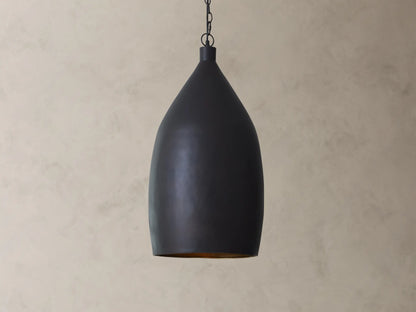 A matte black pendant light with a smooth, teardrop shape hanging from a chain against a beige textured wall.