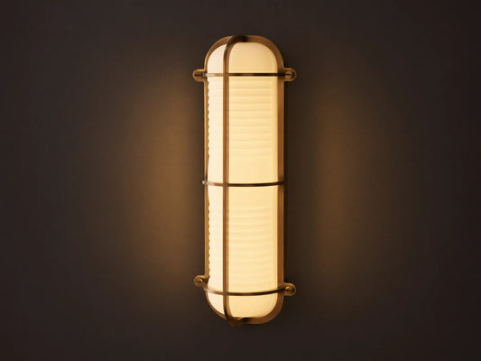 Solomon Outdoor Sconce, vertical, brass-framed, with glowing ribbed milk glass diffuser mounted on a neutral-colored wall.