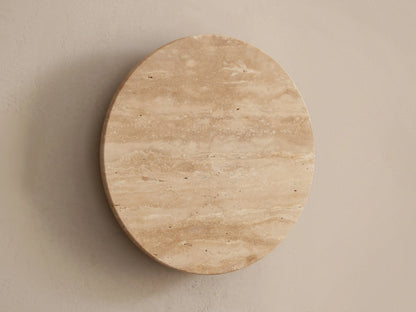Odette Outdoor Sconce: Oval natural stone sconce with horizontal patterns, emitting a warm LED glow on a beige wall.