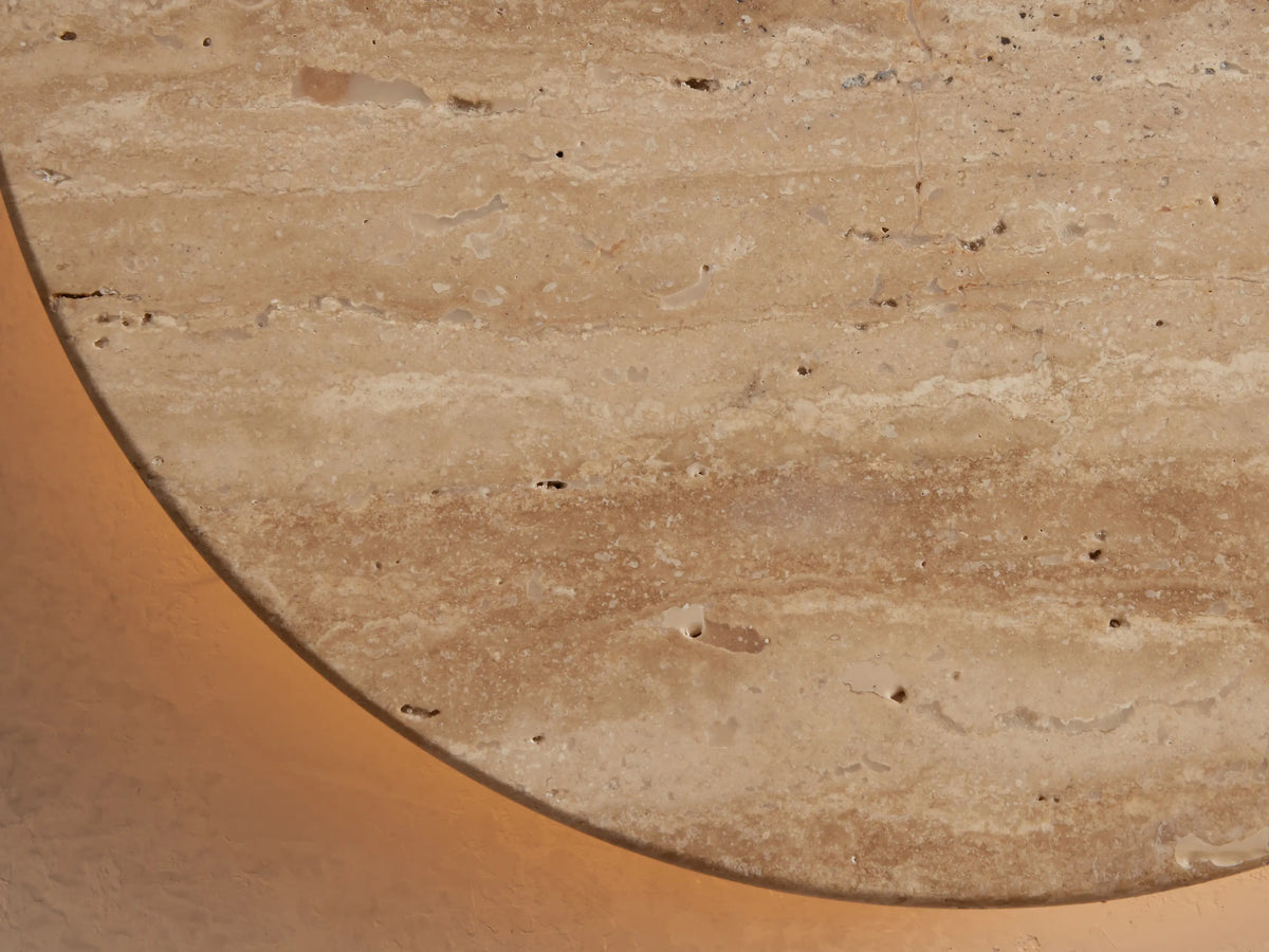 Odette Outdoor Sconce: Oval natural stone with beige & cream horizontal veining, mounted on a light wall.