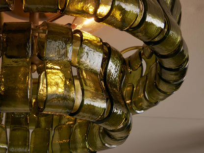 Ghiaccio Flush Mount with layered, wavy olive green textured glass pieces and a round brass ceiling mount on a light ceiling.