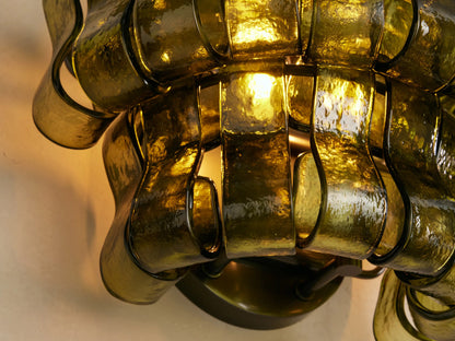 Ghiaccio Sconce: layered wall-mounted light with wavy, textured dark green curved glass panels on a light wall.