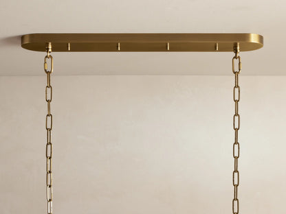 Ghiaccio Oval Chandelier close-up: textured, curved olive glass panels glow warmly, reflecting light in wavy forms.