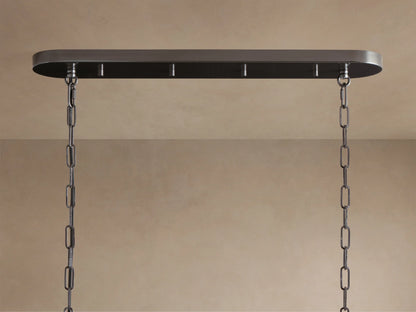 Close-up of Ghiaccio Oval Chandelier. Curved, textured olive green glass panels glow warmly, arranged in overlapping rows.