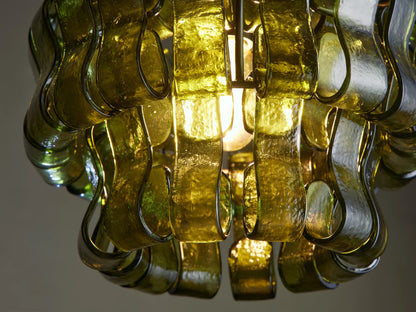 Ghiaccio Pendant, featuring a shade made of layered, wavy translucent green glass pieces, suspended by a dark chain.