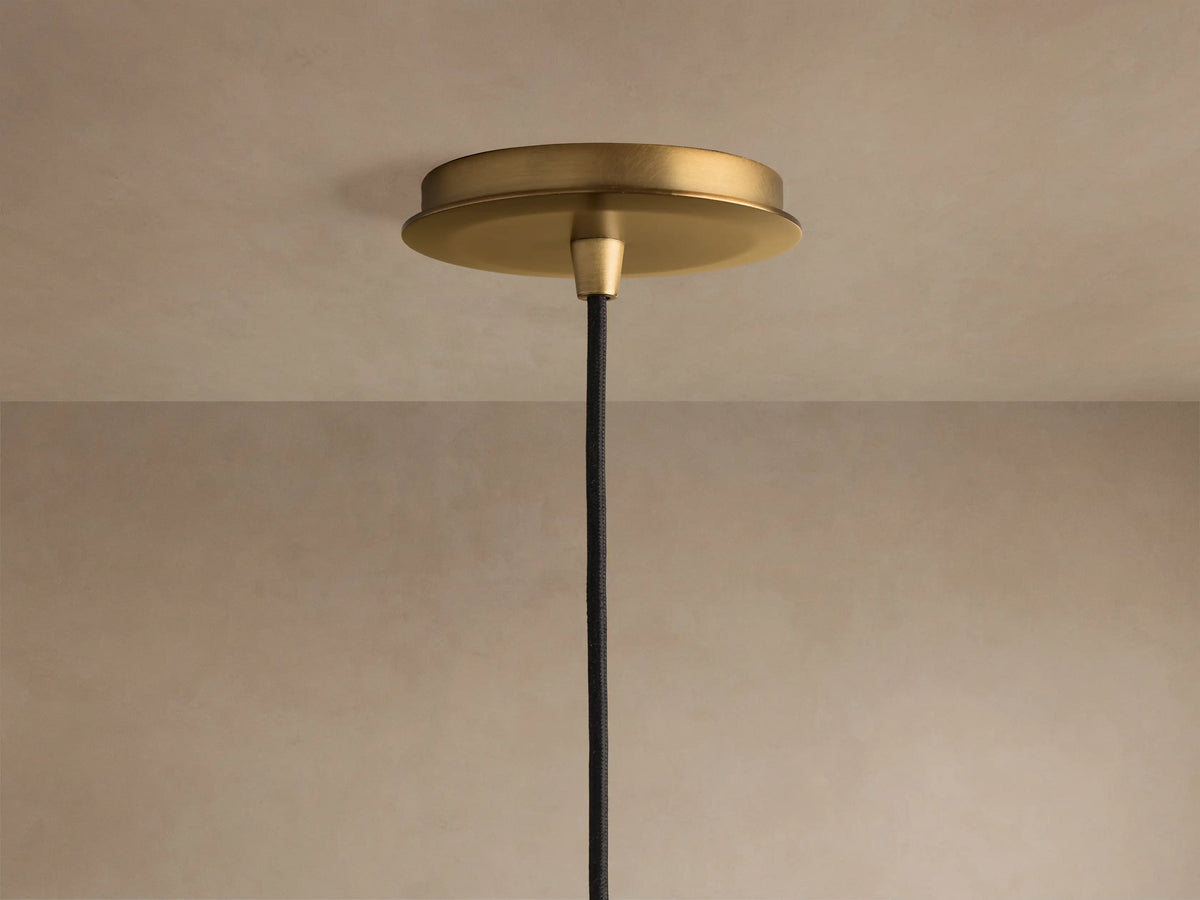 Close-up of a clear, hammered textured glass pendant light with a warm, glowing bulb inside.