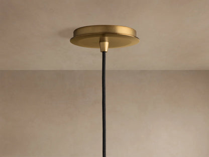 Close-up of a clear, hammered textured glass pendant light with a warm, glowing bulb inside.