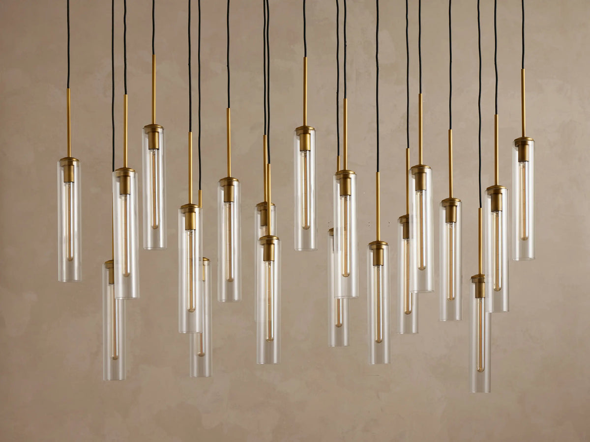 Underside view of a rectangular gold metal canopy with twenty black electrical cords hanging vertically from it.