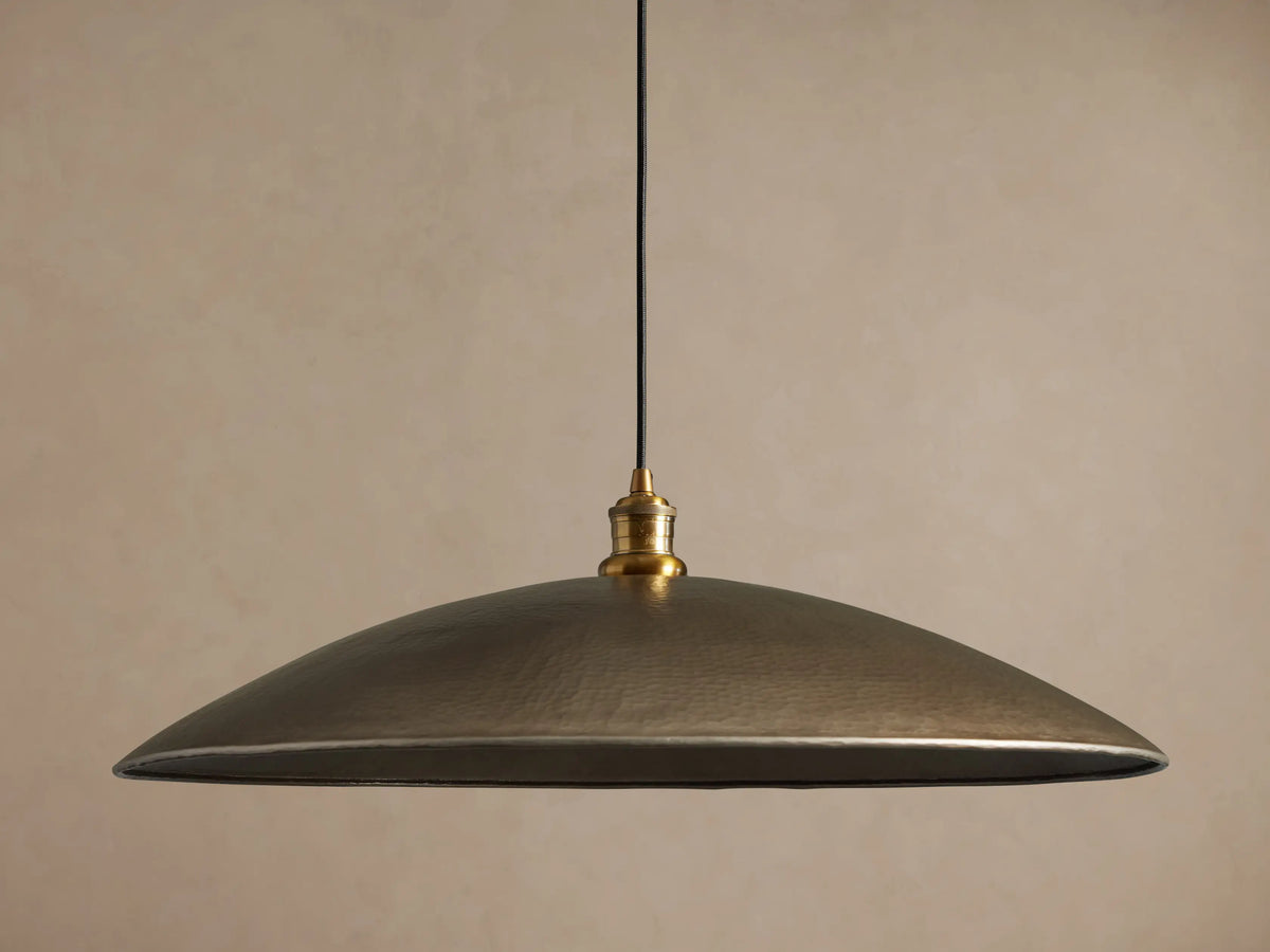Recycled Metal Fan Pendant with wide, hammered brass-finished shade and reflective golden interior, hanging from a black cord.