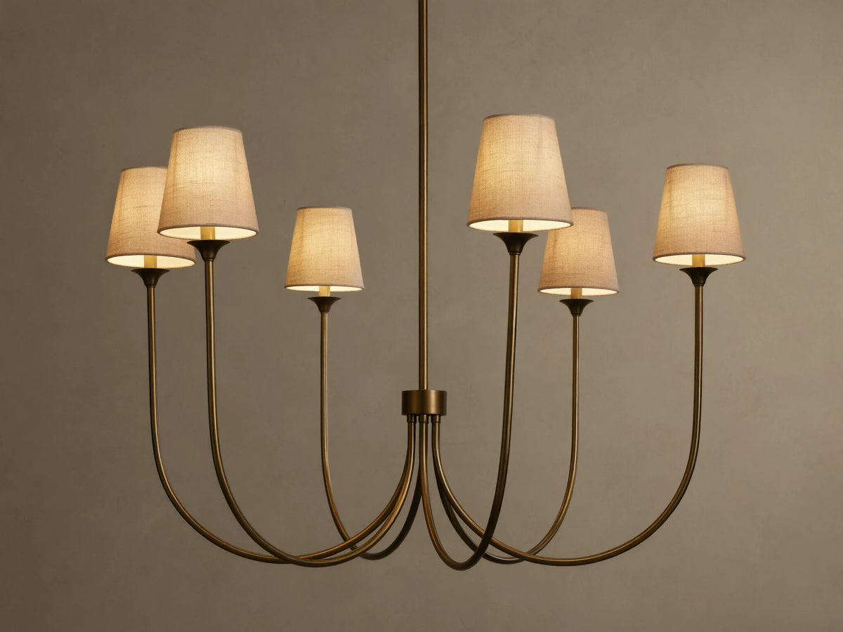 Saige Round Chandelier with a bronze finish, six illuminated off-white tapered fabric shades, hanging against a dark background.