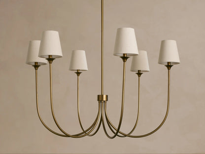 Saige Round Chandelier: Brass finish, six elegantly curved arms holding off-white tapered fabric shades, hanging.
