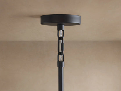 Black ceiling canopy of Saige Round Chandelier attached to a beige ceiling, with a black rod and chain extending down.