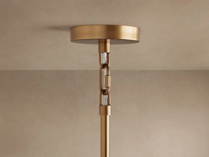 Saige Round Chandelier's brass ceiling canopy connected to a descending extension rod by two chain links with clear glass inserts.