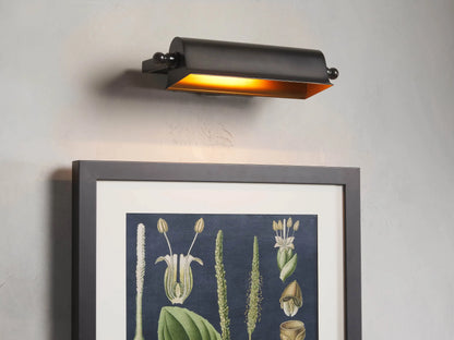 Tremont Bronze Library Sconce with a dark bronze finish, rectangular shade, mounted on a wall, illuminated warm light.