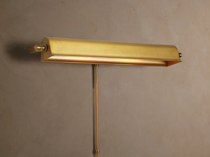 Antiqued metallic Tremont Picture Light Sconce on a textured wall, glowing warmly downwards.